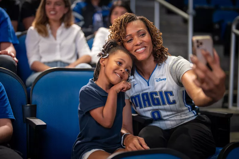 Mother and daughter taking selfie at Orlando Magic game.