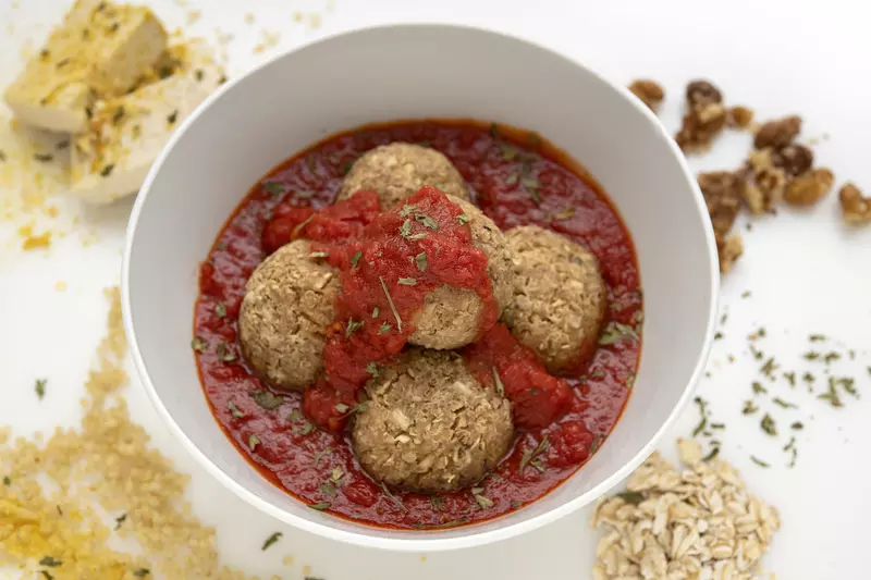 Bowl of nut balls in red sauce with breadcrumb decoration