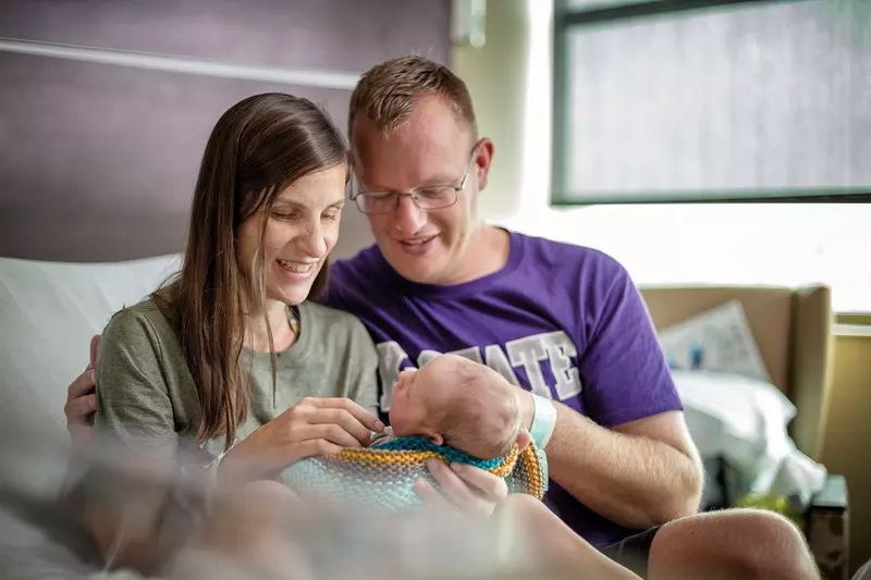 New parents hold their newborn in the hospital.