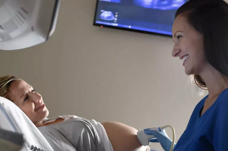 A nurse using an ultrasound on a pregnant mother