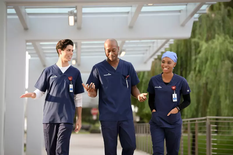 3 nurses walking outdoor corridor 