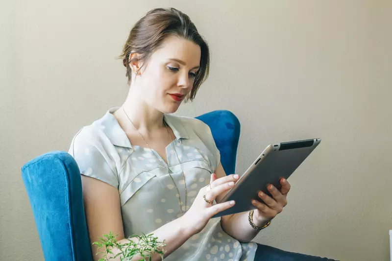 A young caucasian woman reads from her tablet indoors.