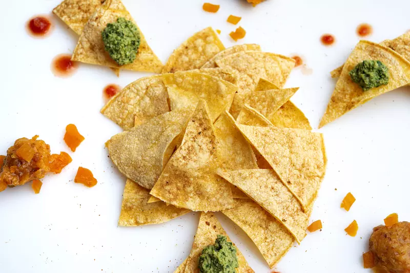 Pile of tortilla chips with salsa and guac.
