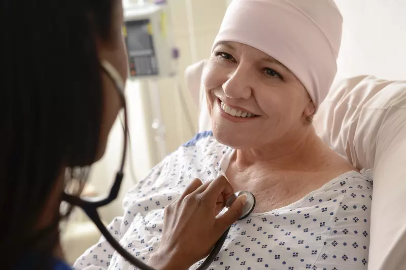 An adult female cancer patient receives treatment from a nurse.