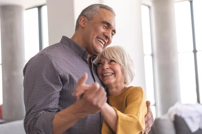 Older Couple dancing together while at home.