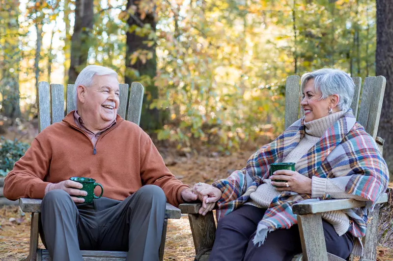 Older man and woman sitting and smiling at each other in the forest