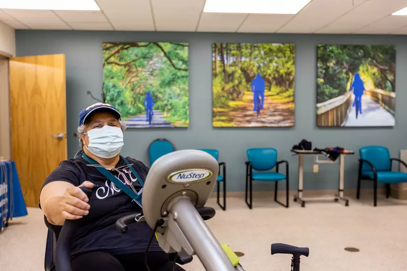 A patient using a cycle machine in the sports rehab room
