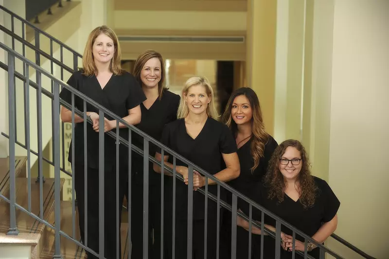 A group of five ladies wearing black clothes standing on the staircase.