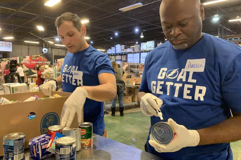 Two male volunteers labeling food donations