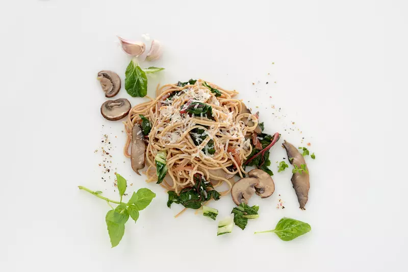 a serving of whole wheat angel hair pasta mixed with greens and mushrooms