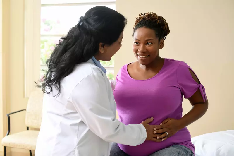 A nurse having a friendly conversation with a patient who is expecting a baby. 