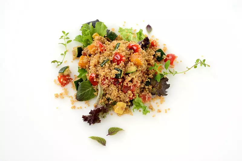a large scoop of cooked quinoa, mixed with colorful squash and peppers
