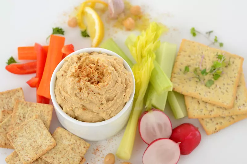 Dish of garmanzo hummus surrounded by crackers and vegetables