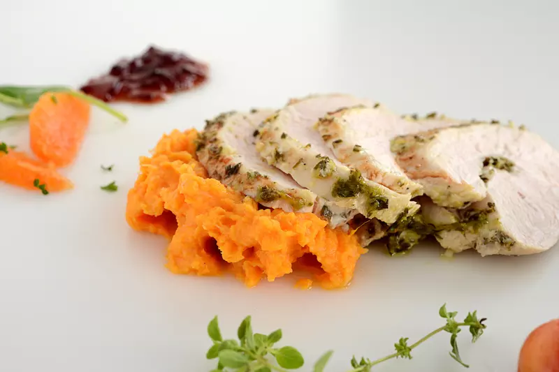 Four slices of turkey breast with sweet potato mash and garnishes