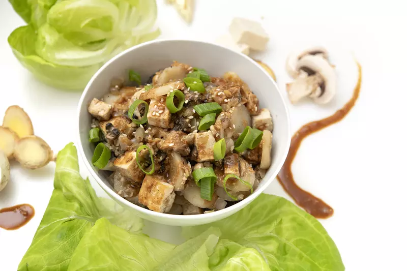 Bowl of tofu chunks and green onions with lettuce garnish