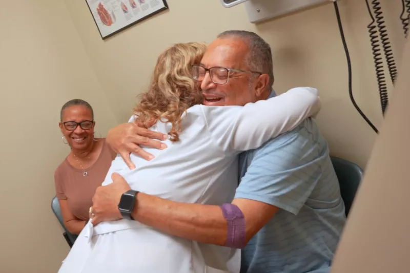 Doctor hugging heart transplant patient.