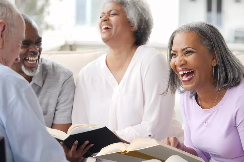 A group of older adults laughing while in a Bible study together.