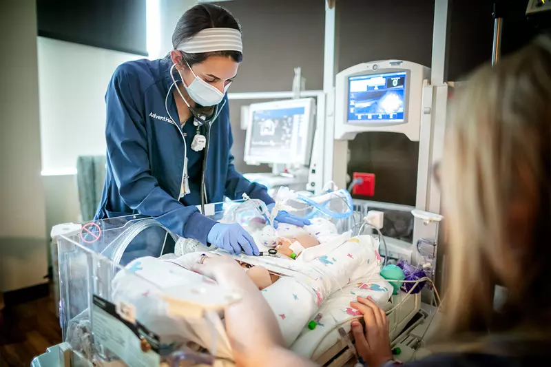Nurse examining a newborn in the NICU.
