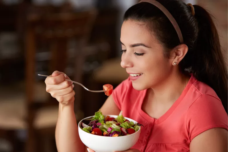 A woman eating a bowl of health food.