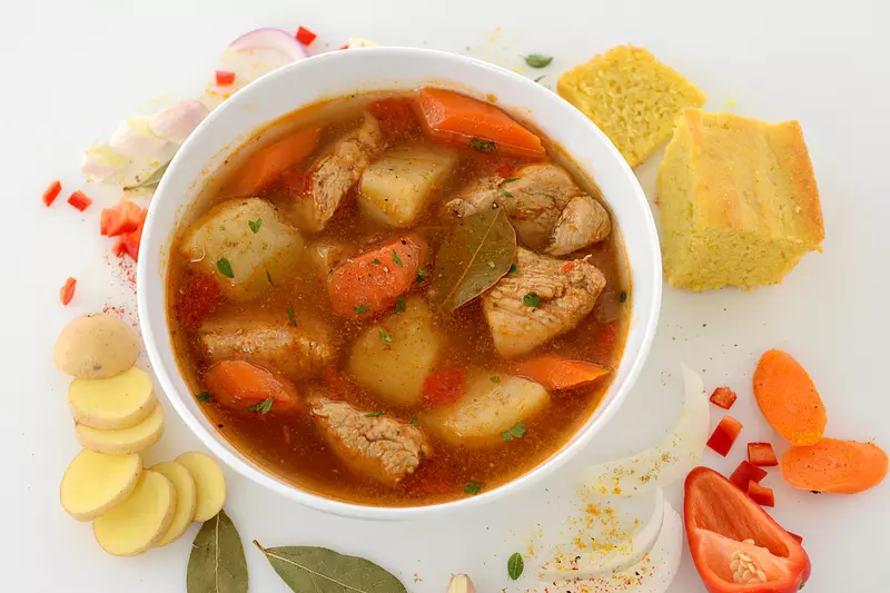 Bowl of chicken fricassee with cornbread and vegetable garnishes