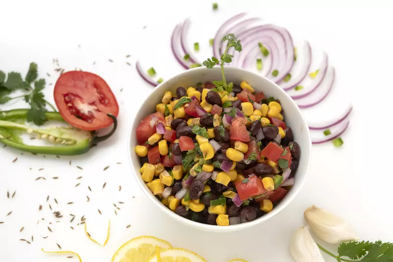 Bowl of black bean salad with vegetable garnishes