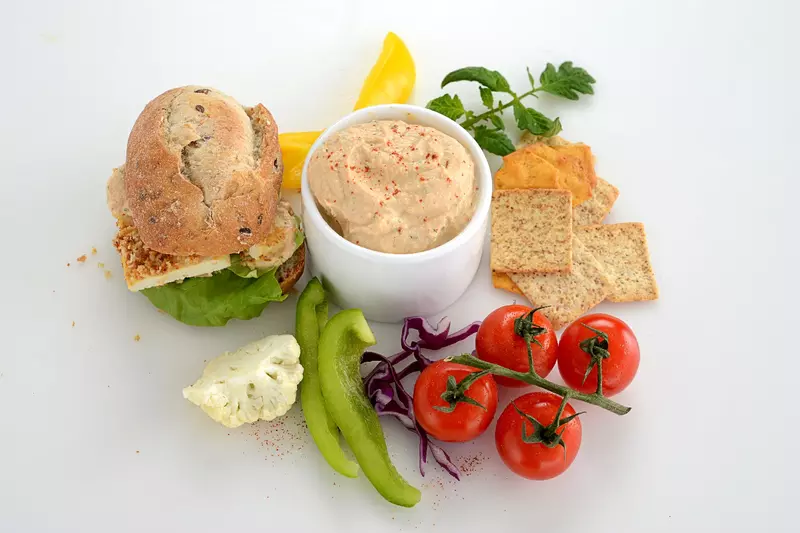 a bowl of creamy dip, surrounded by bread, crackers and fresh vegetables