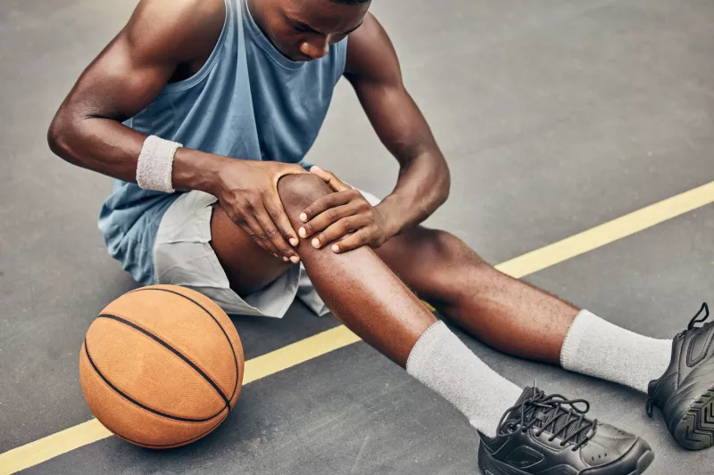 Young male athlete examining his injured knee.