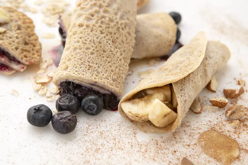 Two crepes filled with blueberries, one crepe filled with potatoes