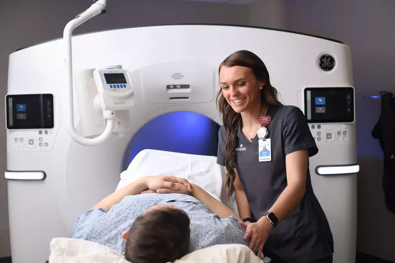 Female imaging technician preparing a male patient for a CT scan.
