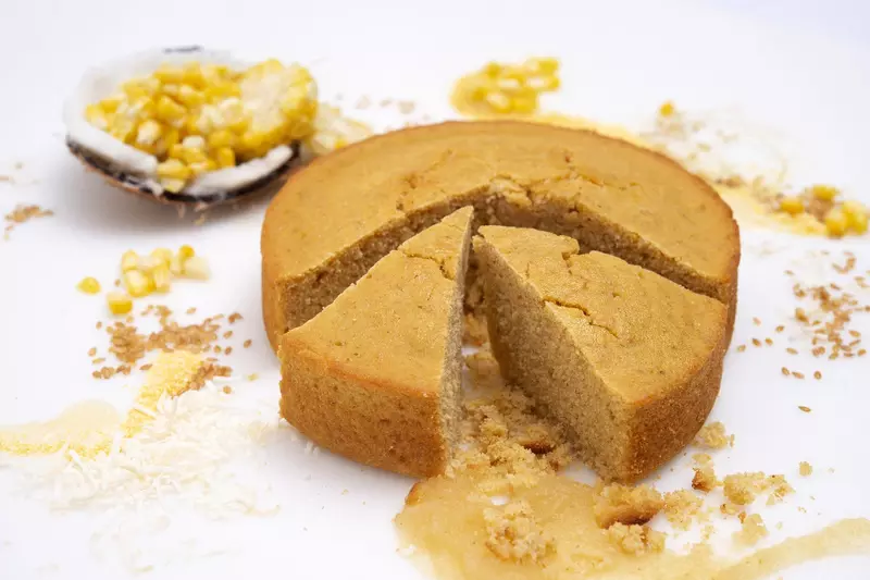a round loaf of freshly baked cornbread, with two slices cut loose