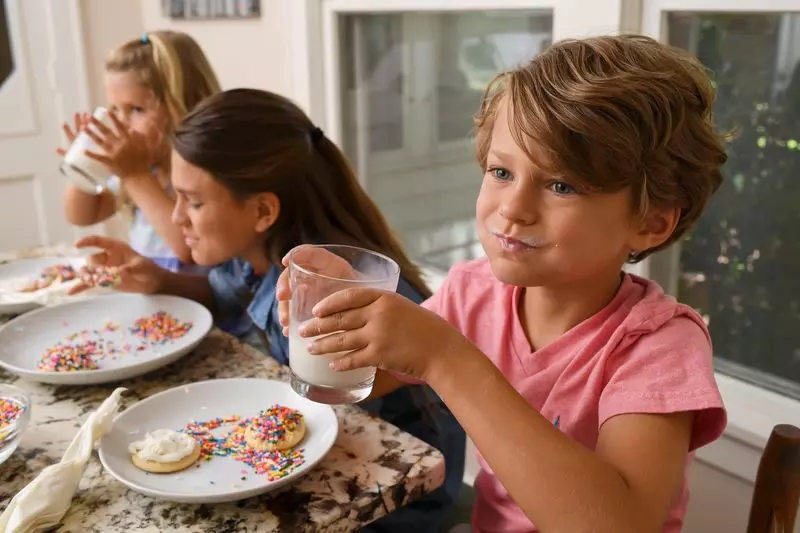 Three kids enjoy homemade cookies and milk