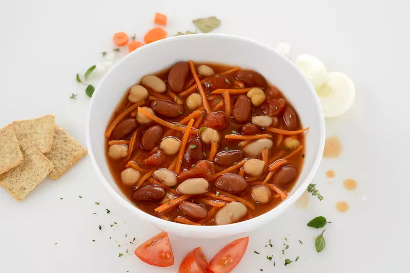 Bowl of Tuscan bean stew with cracker and tomato garnishes