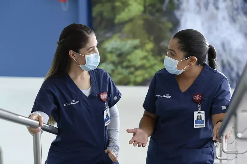 two masked female nurses walking up stairs talking to each other