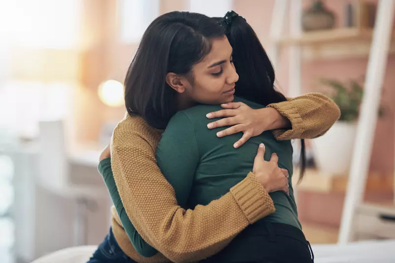 Two women hugging while at home.