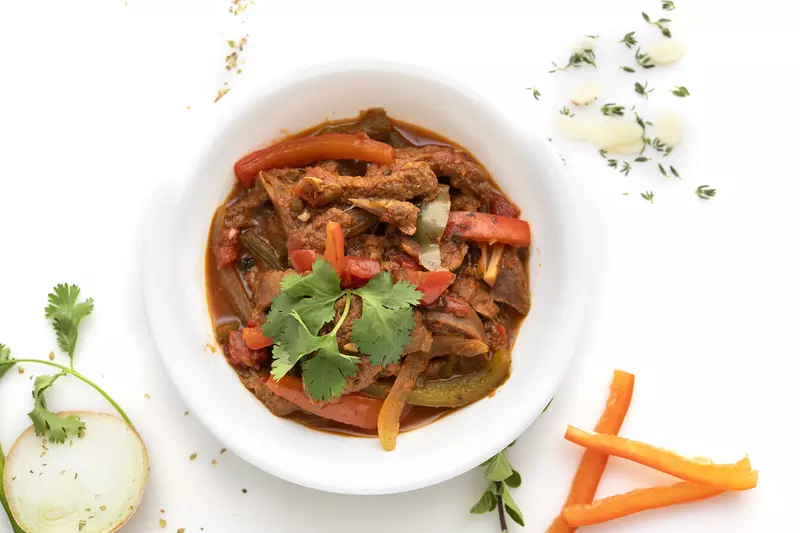 Bowl of ropa vieja stew with parsley and carrot garnishes