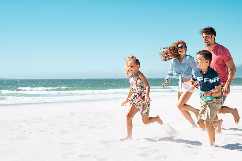 A happy family running together on the beach.
