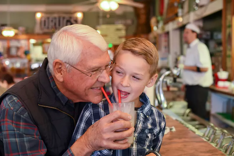 Grandpa and Grandson at a soda fountain.