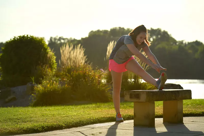 A young woman stretching in the park during the sunset.