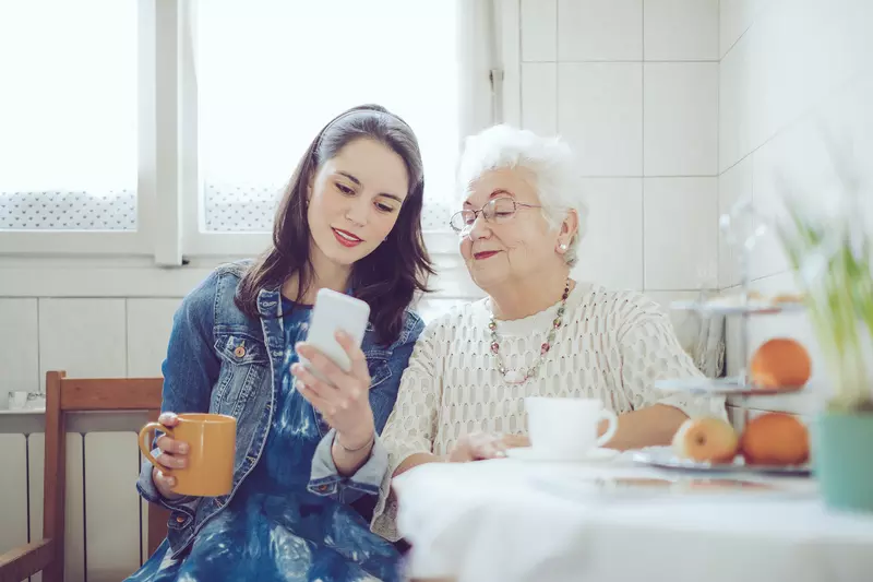 A young woman with an older women checking a cell phone