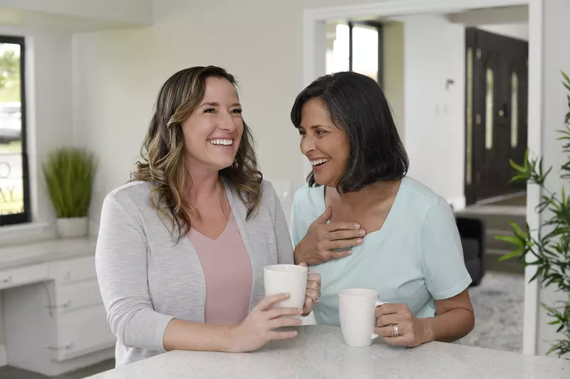 Two women laughing while having coffee together