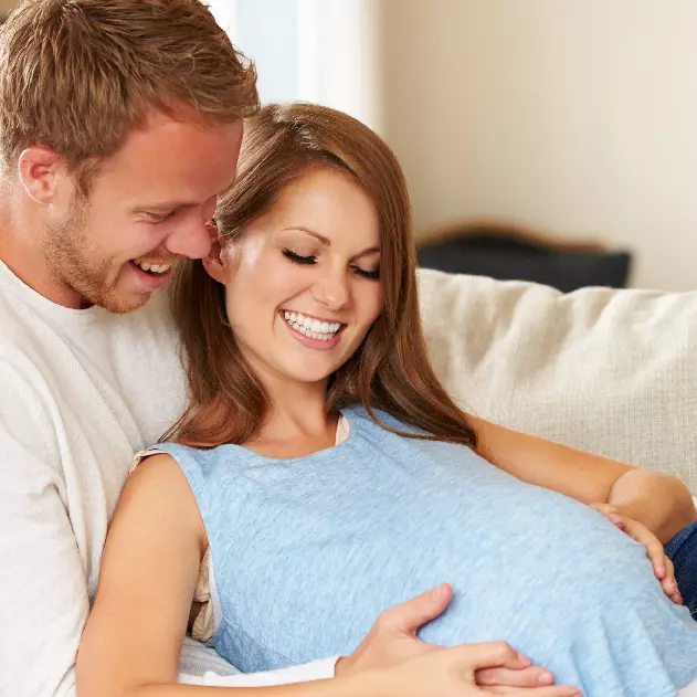 preganant couple sitting on couch