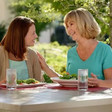 Two women sitting at outdoor table talking and eating