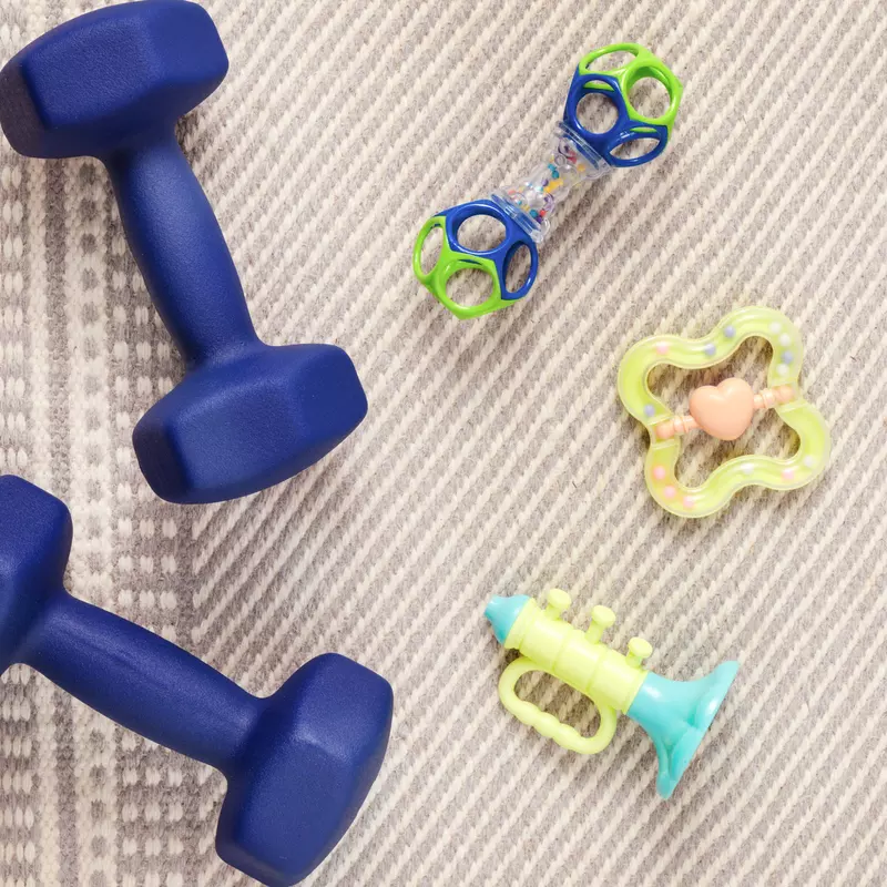 Blue small dumbbells and assorted baby toys on a beige carpet