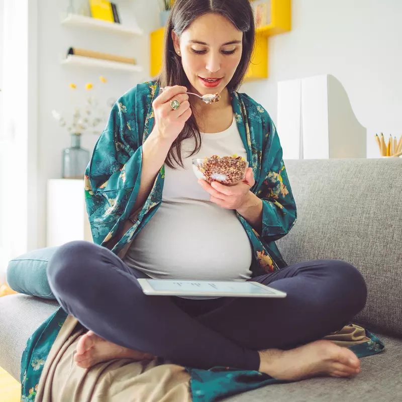 A pregnant woman eating breakfast. 