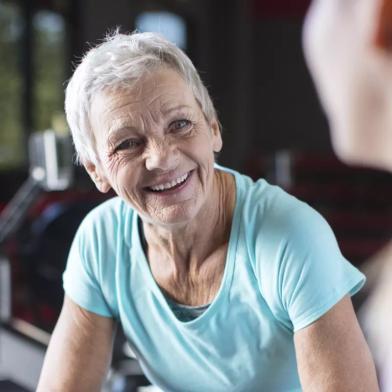 An older woman takes a break from working out on a rowing machine