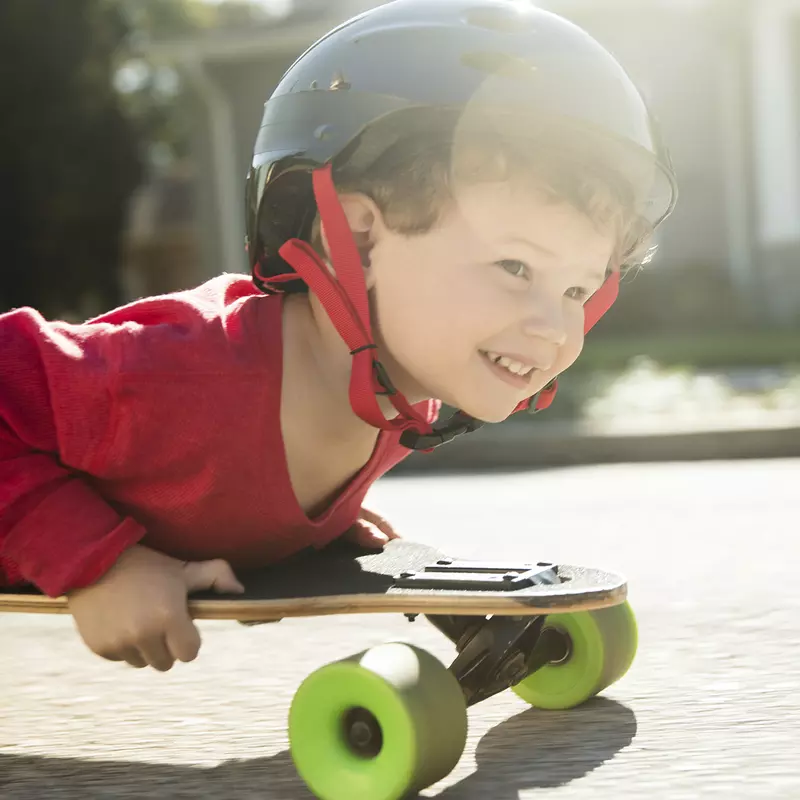 A young boy rides on a skateboard on his belly. 