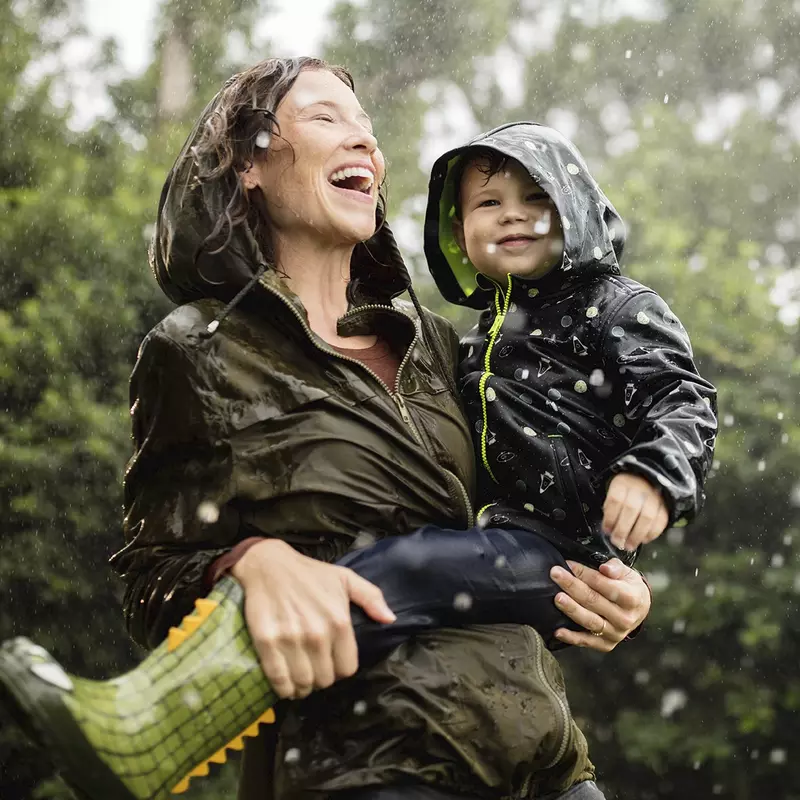 A mother and her young son play in the rain.