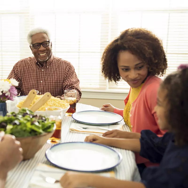 An African American family sits down at the table for a healthy meal.