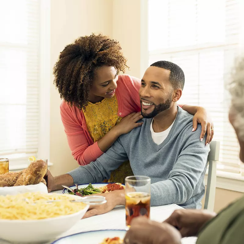 An African American family gathers around the dinner table for a meal of spaghetti.