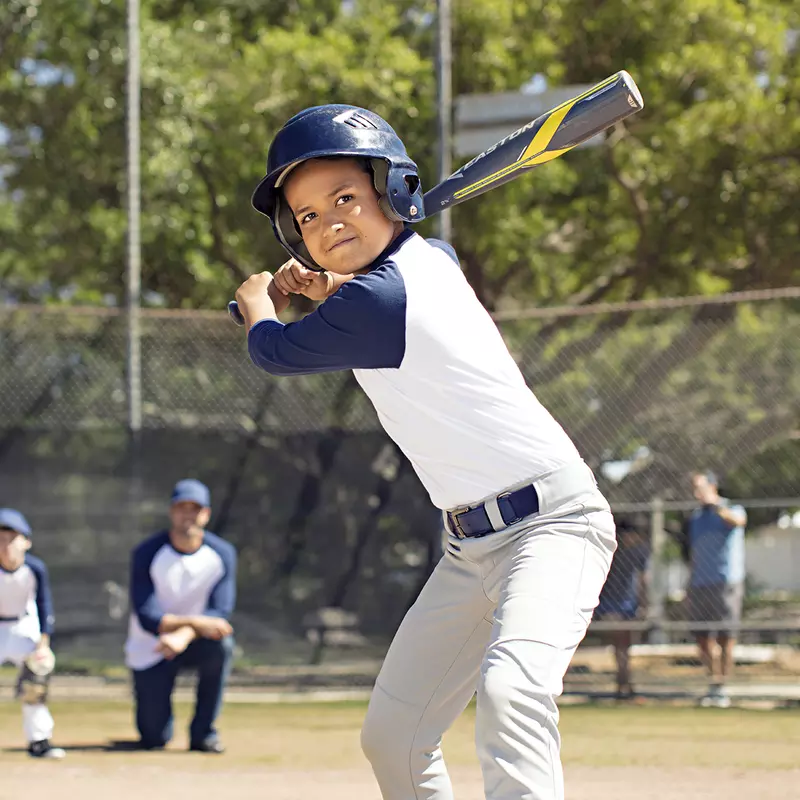 A young boy prepares to bat during an afternoon baseball game.